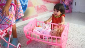 Девочка играет в дочки-матери. Играет с куклой, качает в колыбельке.