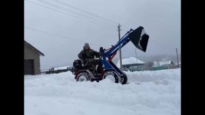 Самодельный трактор чистит снег.