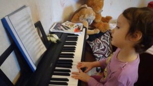 Маленькая девочка играет на пианино и поет