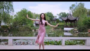 Девушка танцует в розовом длином облегающем платье и белых туфлях на шпильке