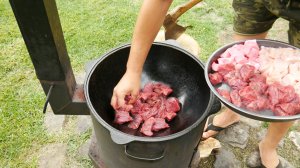 Густой суп из трех видов мяса в казане на костре.