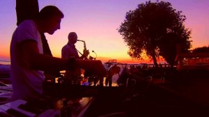 Saxophonist playing in the sunset with a DJ