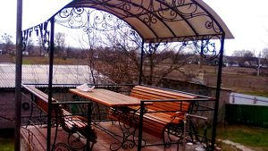 Дачная беседка на террасе в саду, стол, скамейки, крыша арочная, ковка из металла, дизайн,