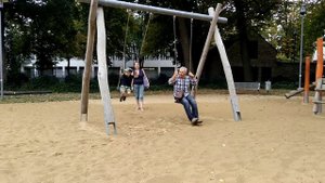 Дед с внуком катаются на качелях.