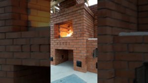 Печной комплекс барбекю из красного кирпича в небольшой беседке.