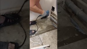 сбивает перфоратором бетонный бордюр в ванной.
