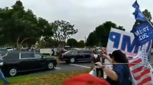 مقطع فيديو لرجل أمريكي يركض بجانب سيارة بايدن، وهو يحمل علما كتب عليه "Trump 2024"