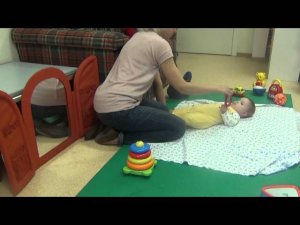 Ребенок тянется к игрушке в положении лежа на спине