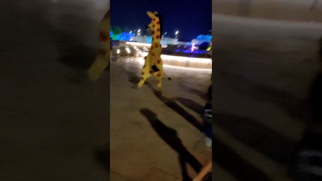 Жираф гуляет по парку