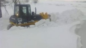 Бульдозер SHANTUI, пробивает дорогу в глубоком снегу.