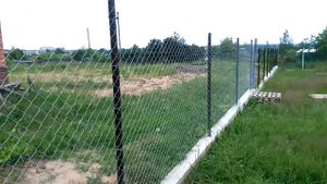Вариант забора из сетки рабицы на участке с уклоном