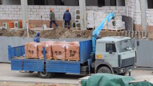 Автокран выгружает кирпич из крана манипулятора МАЗ