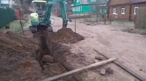 Рощино мини экскаватор копает траншею под водопровод.