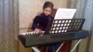 Пятилетняя девочка играет на синтезаторе.