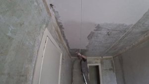 Снятие старой краски и шпаклевки с потолка с помощью скребка в малой комнате