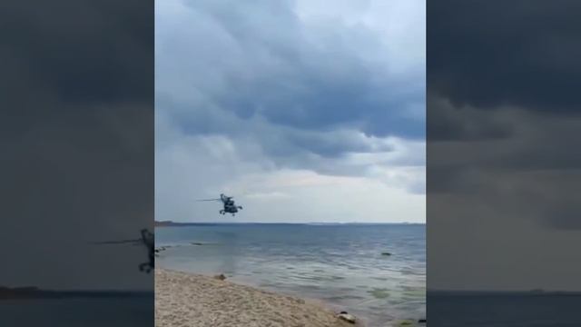 Российский военный вертолёт пролетает над побережьем Крыма на малой высоте.