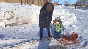 Настя и Кирилл катаются на санках с мамой и папой с горки.