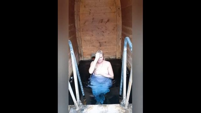 Крещение в купели Рождественно. Красивая девушка в сорочке погружается в ледяную воду.