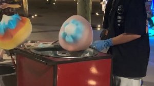 Уличный торговец делает цветы из сладкой ваты.