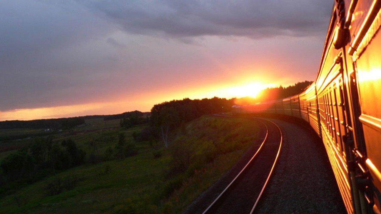 За тем поворотом дороги оказалась деревня. Поезд на закате. Красивый вид из поезда. Железная дорога закат. Вид из окна поезда.