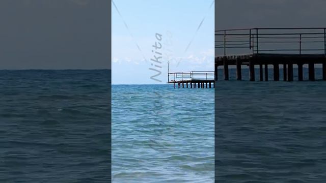 Vertical video. Waters of the lake Issyk-Kul in the background of mountains, beach town of Cholpon