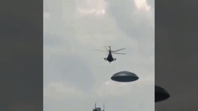 Военный вертолет сопровождает дискообразный летающий объект.