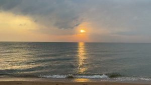 Sunrise at sea in a light rain and the sound of the surf