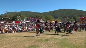 Massed Pipes & Drums playing Cock o' the North on the march during 2022 Ballater Highland Games