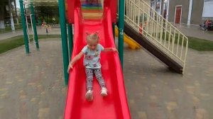 Милана играет на детской площадке. Катается на горках.