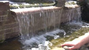 Кристально чистая вода в пруду. Водопад работает как орошаемый фильтр.