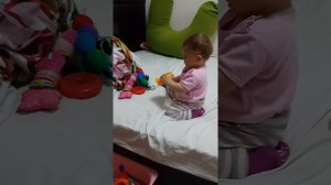 Малышка 10 месяцев,  кладет игрушки в коробочку.