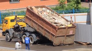 Пухтовоз готовится к отъезду, задвигает мусорный контейнер.
