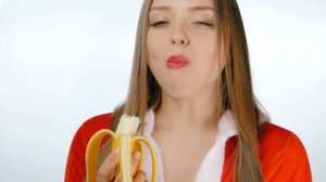 Молодая девушка в одежде снегурочки ест банан. A young girl dressed as a Snow Maiden eats a banana.