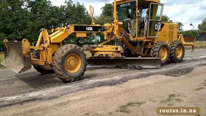Автогрейдер CAT140K срезает колею на асфальте