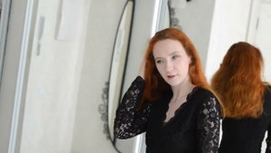 Рыжеволосая девушка в чёрном платье.