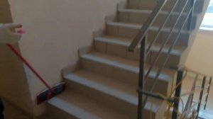Мужик пылесосит и моет полы в подъезде.
