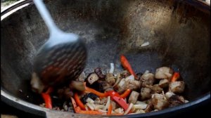 Картошка со свининой и грибами тушёная в томате в казане на костре.