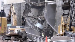 Demolition excavator demolishing part of a concrete (and steel) building
