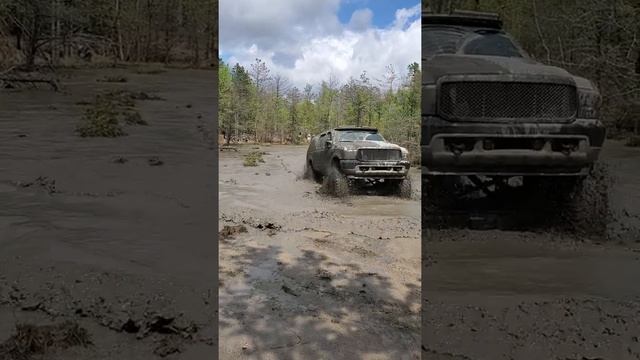 Lifted ford excursion going through a mud hole