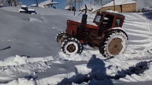 Зима, очередной день в селе. Трактор Т-40 буксует на снегу.