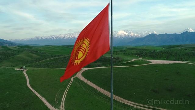 Флаг Кыргызстана и зелёные холмы