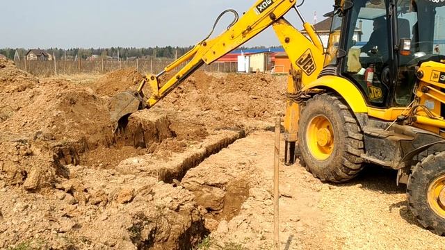 Экскаватор-погрузчик JCB копает землю под подвал частного дома / Ленточный фундамент без опалубки