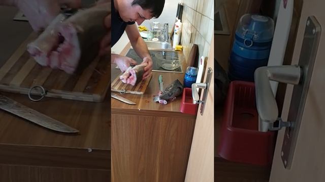 Андрей чистит осетра.