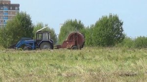 Трактор собирает сено