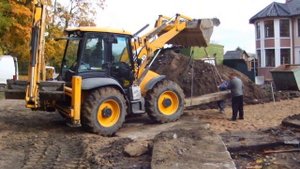 Экскаватор-погрузчик JCB 4 CX укладывает дорожные плиты