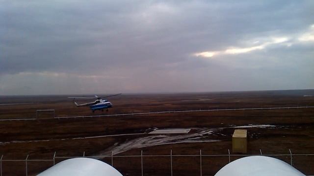 Вертолет Ми - 8  летит над тундрой и заходит на посадку. Месторождение нефти Лукойл.
