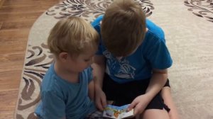 Ребенок читает сказку своему младшему брату. A child reads a fairy tale to his younger brother.