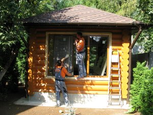 Цветные пластиковые окна в деревянной беседке из оцилиндрованного бревна.