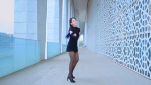 Девушка танцует в синем платье, в черных колготках и туфлях на шпильке.