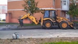 Снятие старого асфальта. Ремонт пешеходной дорожки. Трактор с ковшом и отбойным молотом